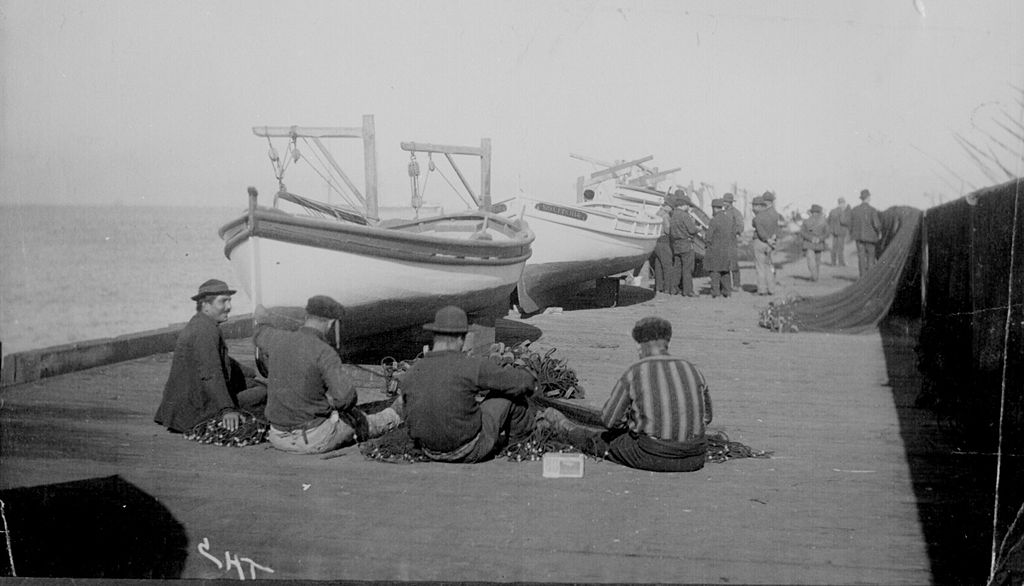 Italian fishermen mending nets on wharf at foot of Union Street in San Francisco